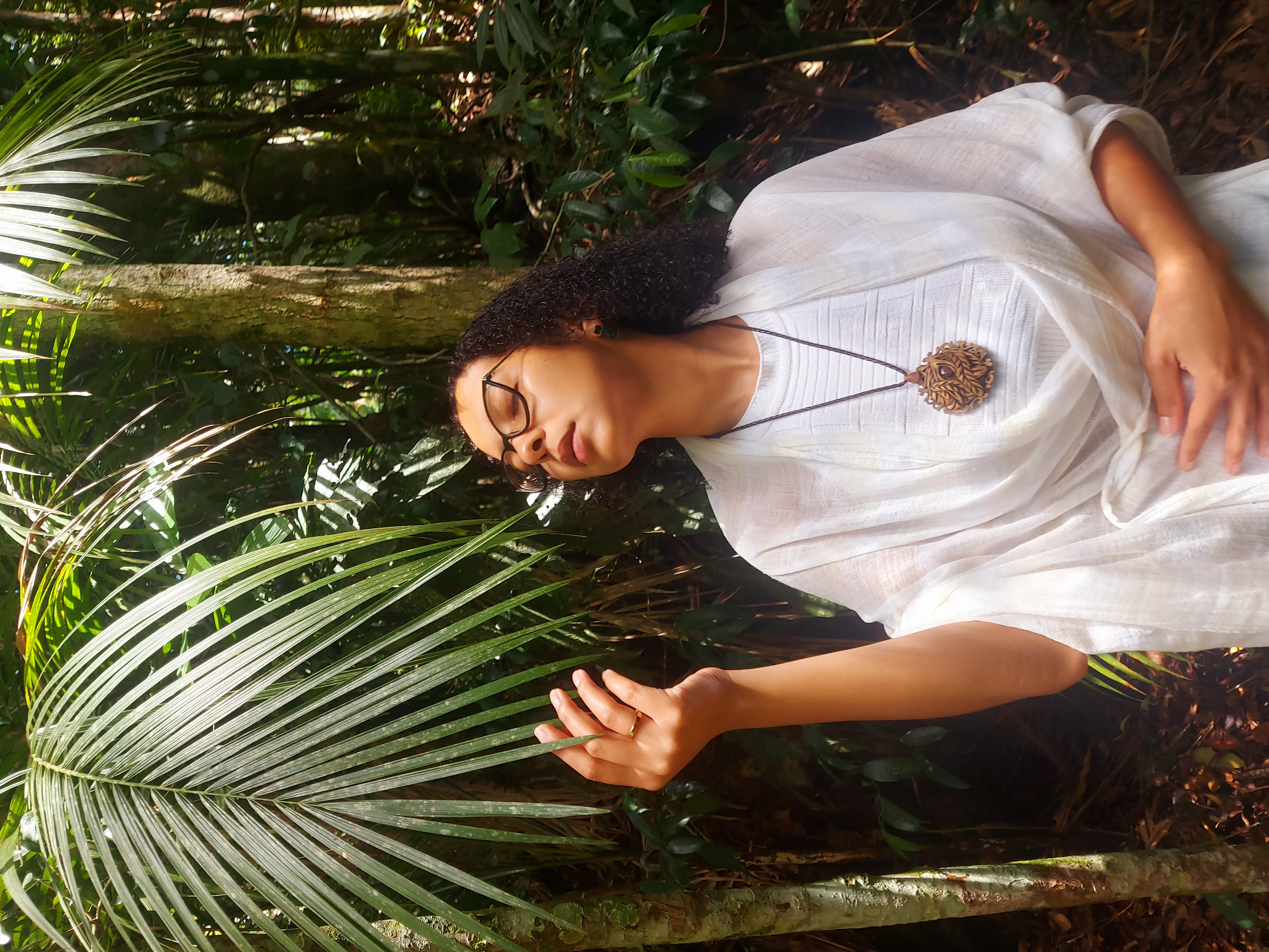 Ita entre plantas do bosque, de olhos fechados, em contato com a natureza
